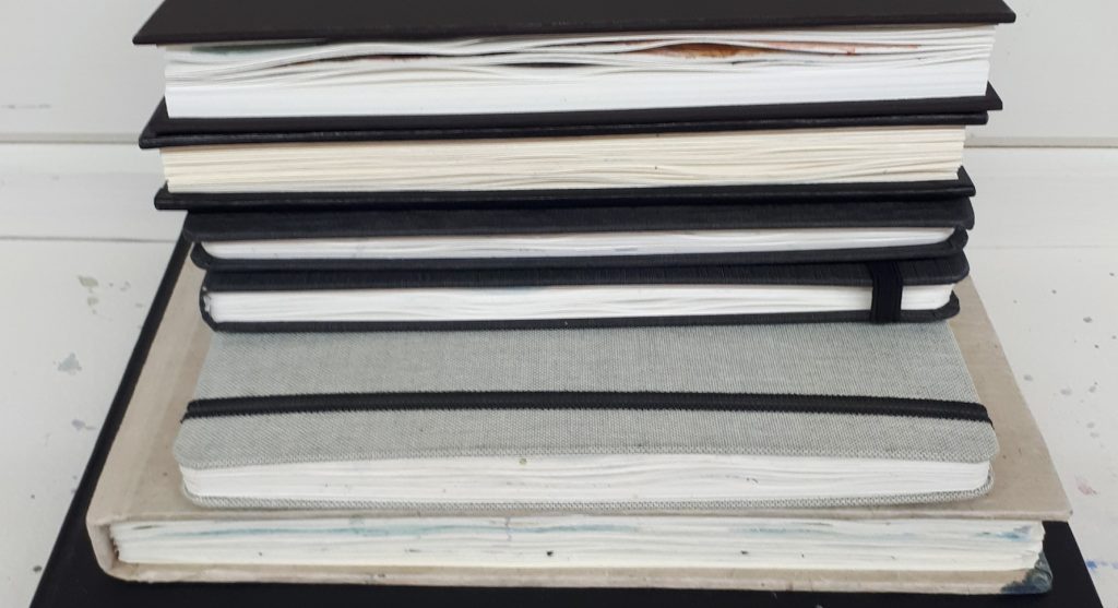 A pile of artist sketchbooks