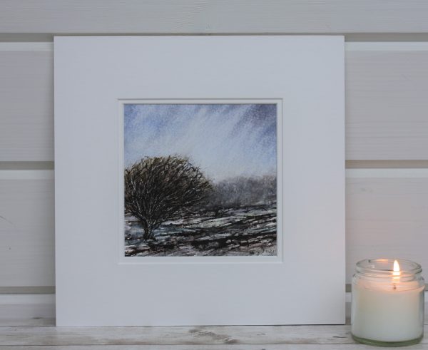 Windswept tree painting in a square mount next to a candle